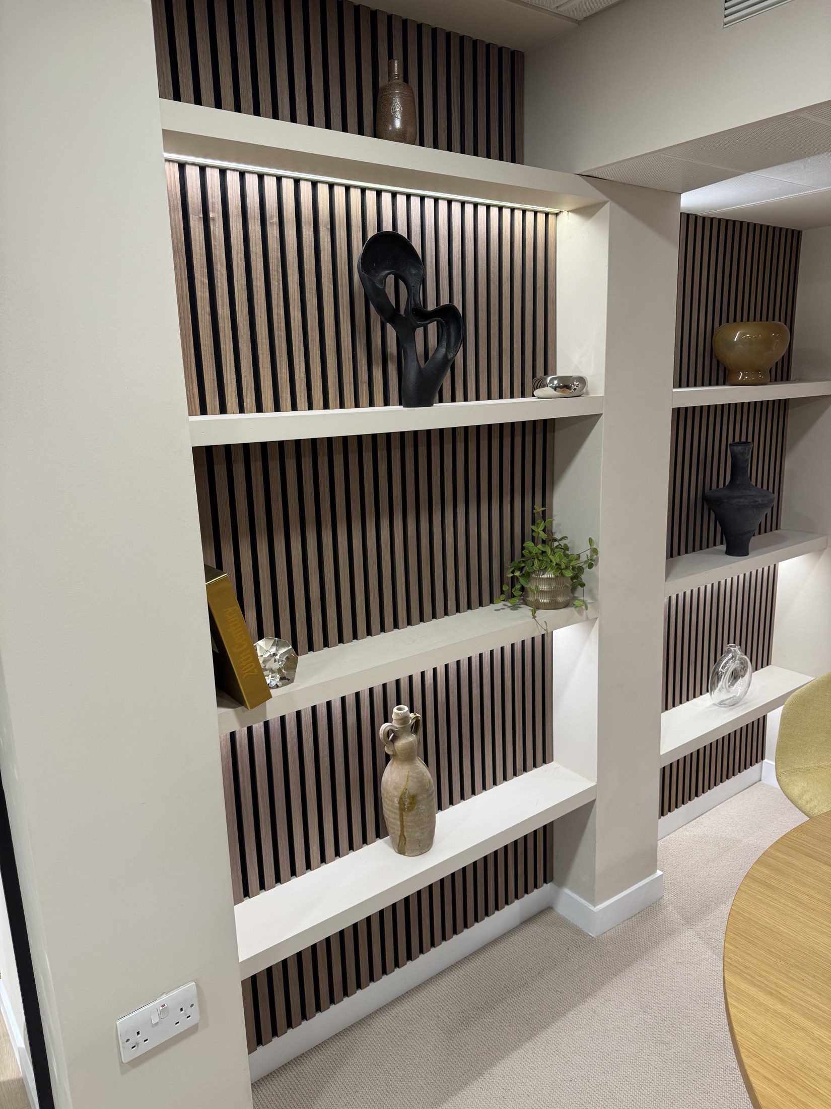 Illuminated shelves with ceramics, sculpture and wood-slat detailing