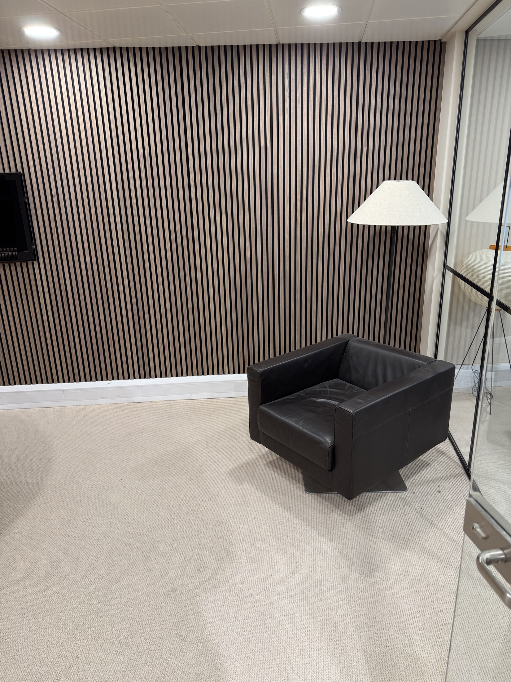 Another angle of the armchair, floor lamp and wood-slat wall